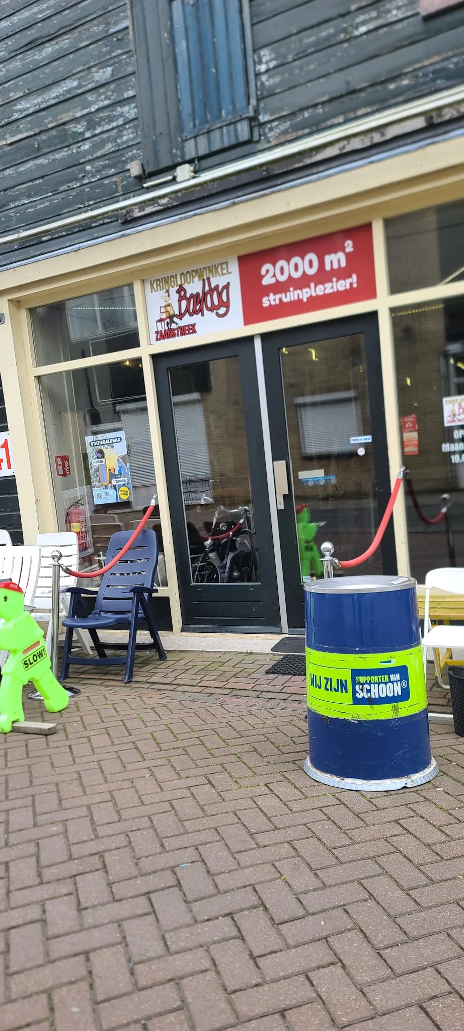 Winkelvoorkant met glazen deur, blauwe stoelen en rode slangen op het terras