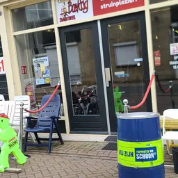 Winkelvoorkant met glazen deur, blauwe stoelen en rode slangen op het terras