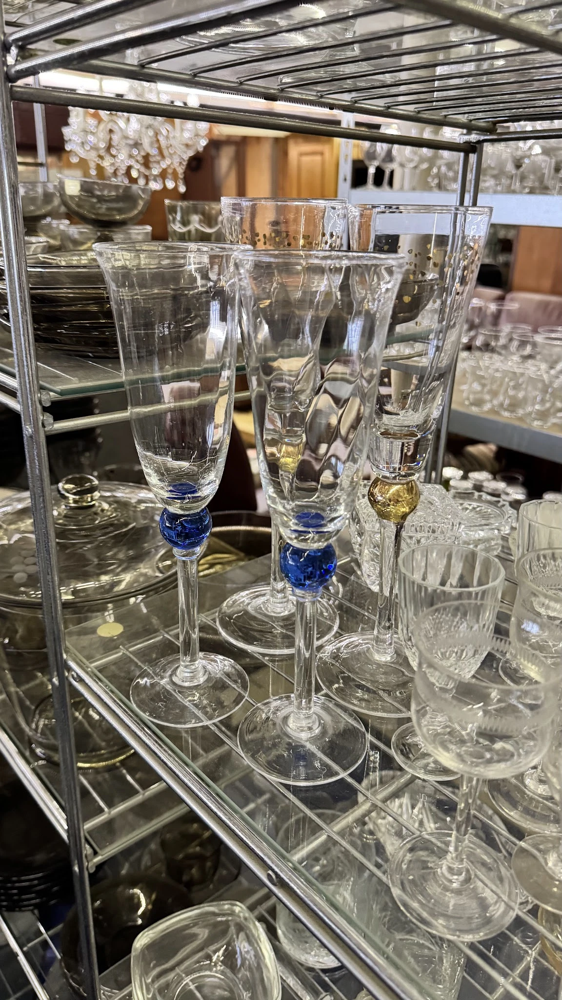 Glazen champagneglazen met blauwe decoratie aan de voet, uitgestald in een vitrine