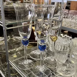 Glazen champagneglazen met blauwe decoratie aan de voet, uitgestald in een vitrine