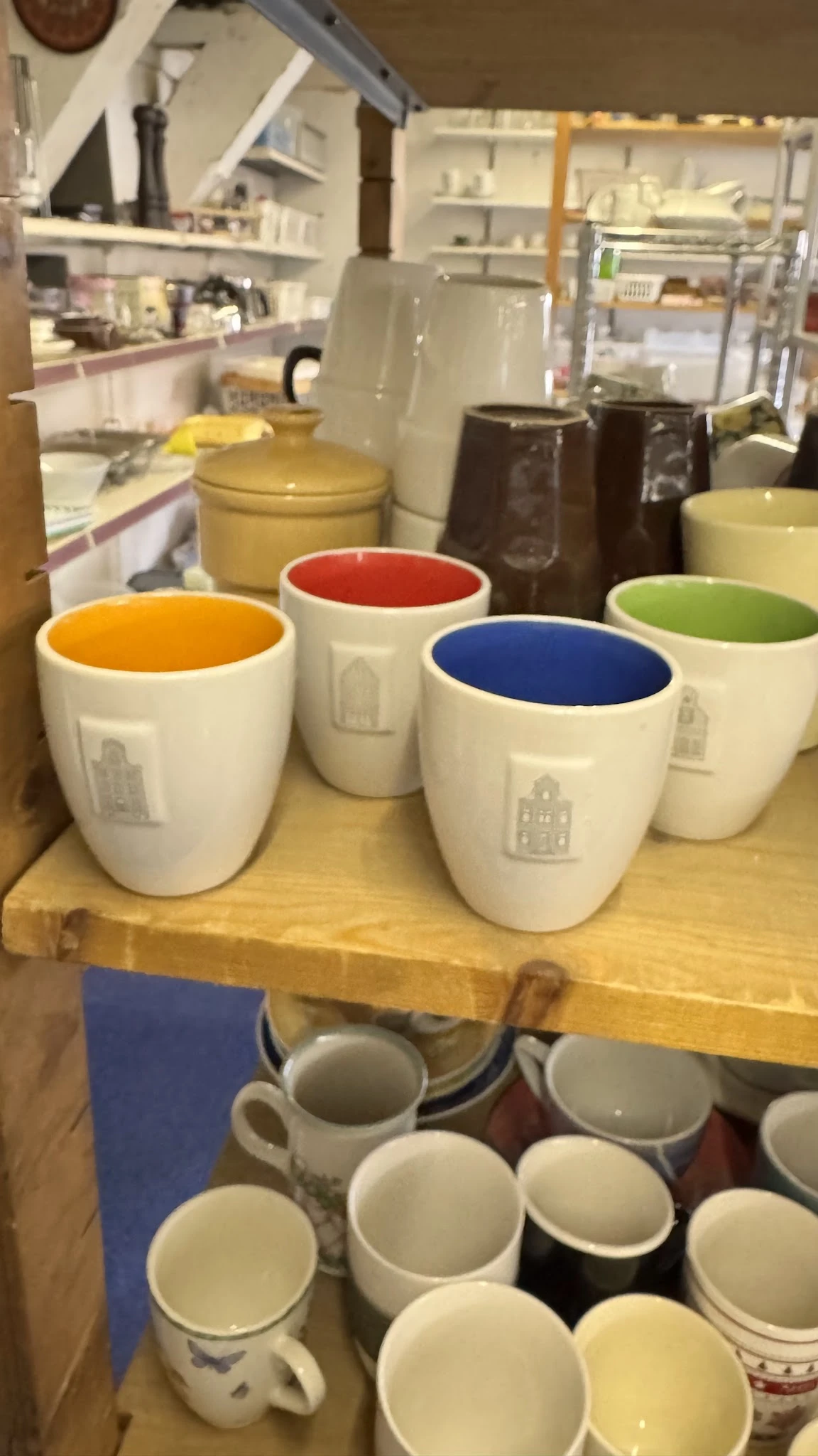 Vier witte koffiekopjes met gekleurde binnenkant (oranje, rood, blauw, groen) en huisje-motief