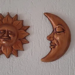Twee houten decoratieve wandstukken: een lachende zon en een grijnzende maan