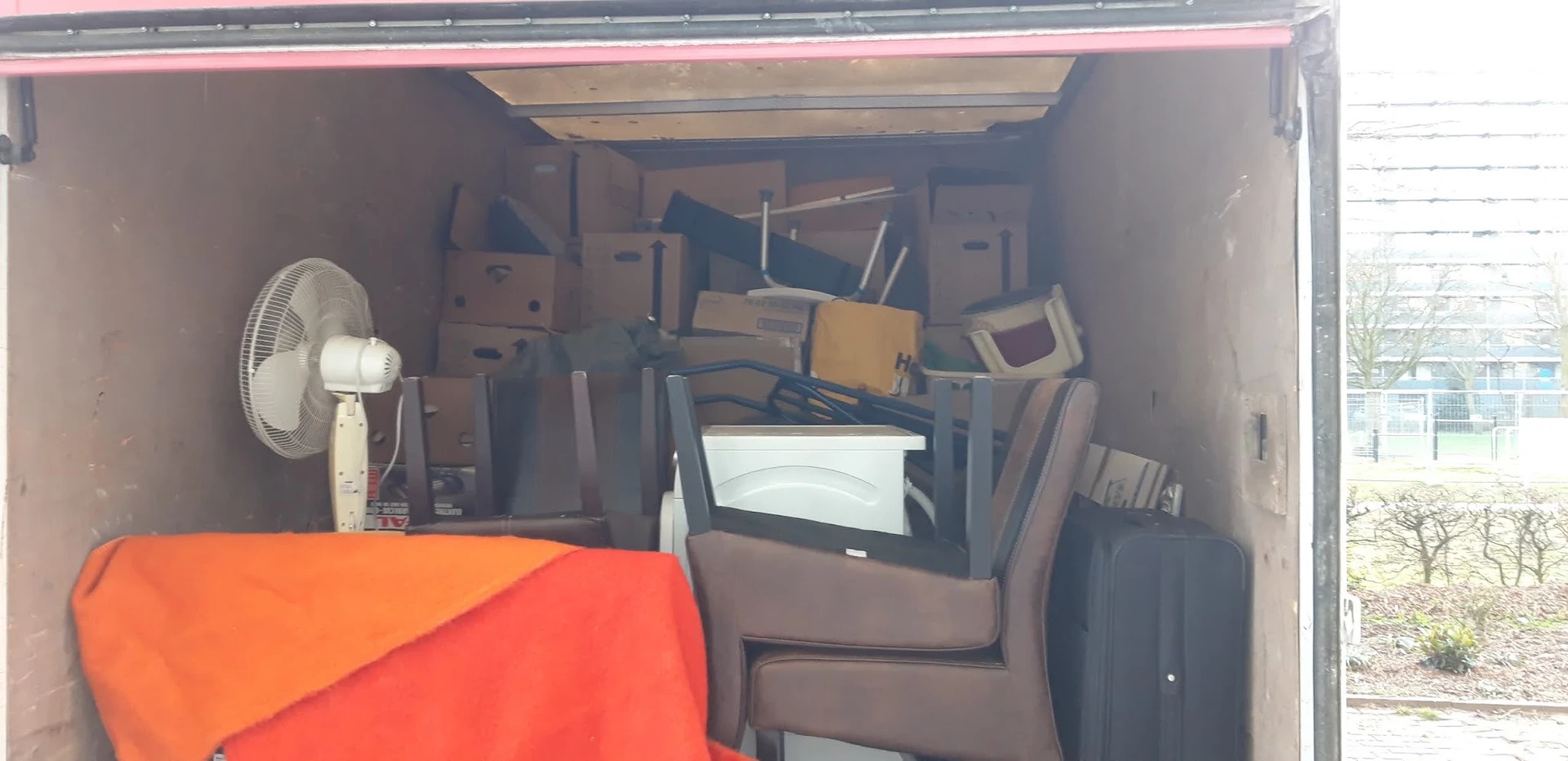 Binnenzijde van een bestelwagen vol met dozen, huishoudelijke artikelen en gebruikte spullen