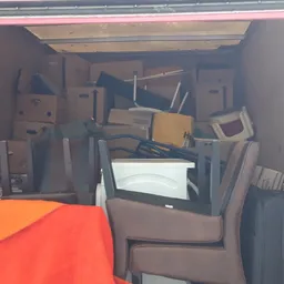 Binnenzijde van een bestelwagen vol met dozen, huishoudelijke artikelen en gebruikte spullen