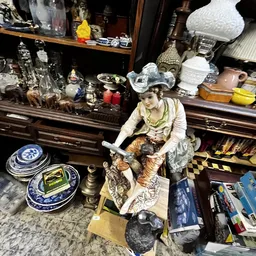 Diverse vintage en antieke voorwerpen uitgestald in een kringloopwinkel, waaronder porselein, beeldjes en decoratieve items o