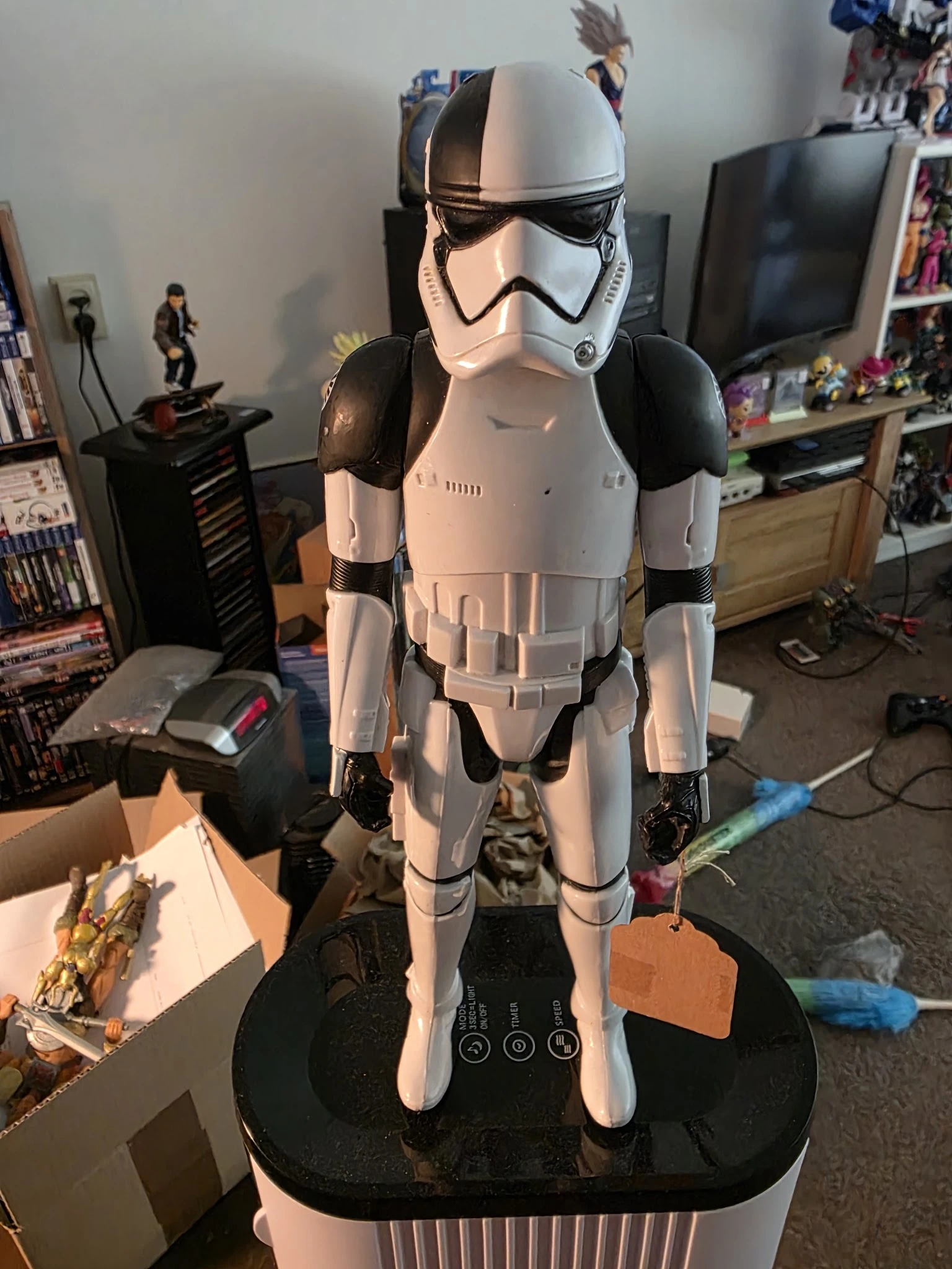 Stormtrooper-kostuum of actiefiguur in wit en zwart, uitgestald in een woonkamer met verzamelingen op de achtergrond