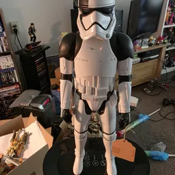 Stormtrooper-kostuum of actiefiguur in wit en zwart, uitgestald in een woonkamer met verzamelingen op de achtergrond