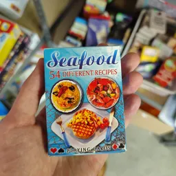 Speelkaartenset met zeevrouchtrecepten in een hand, op de achtergrond onscherpe winkelrek.