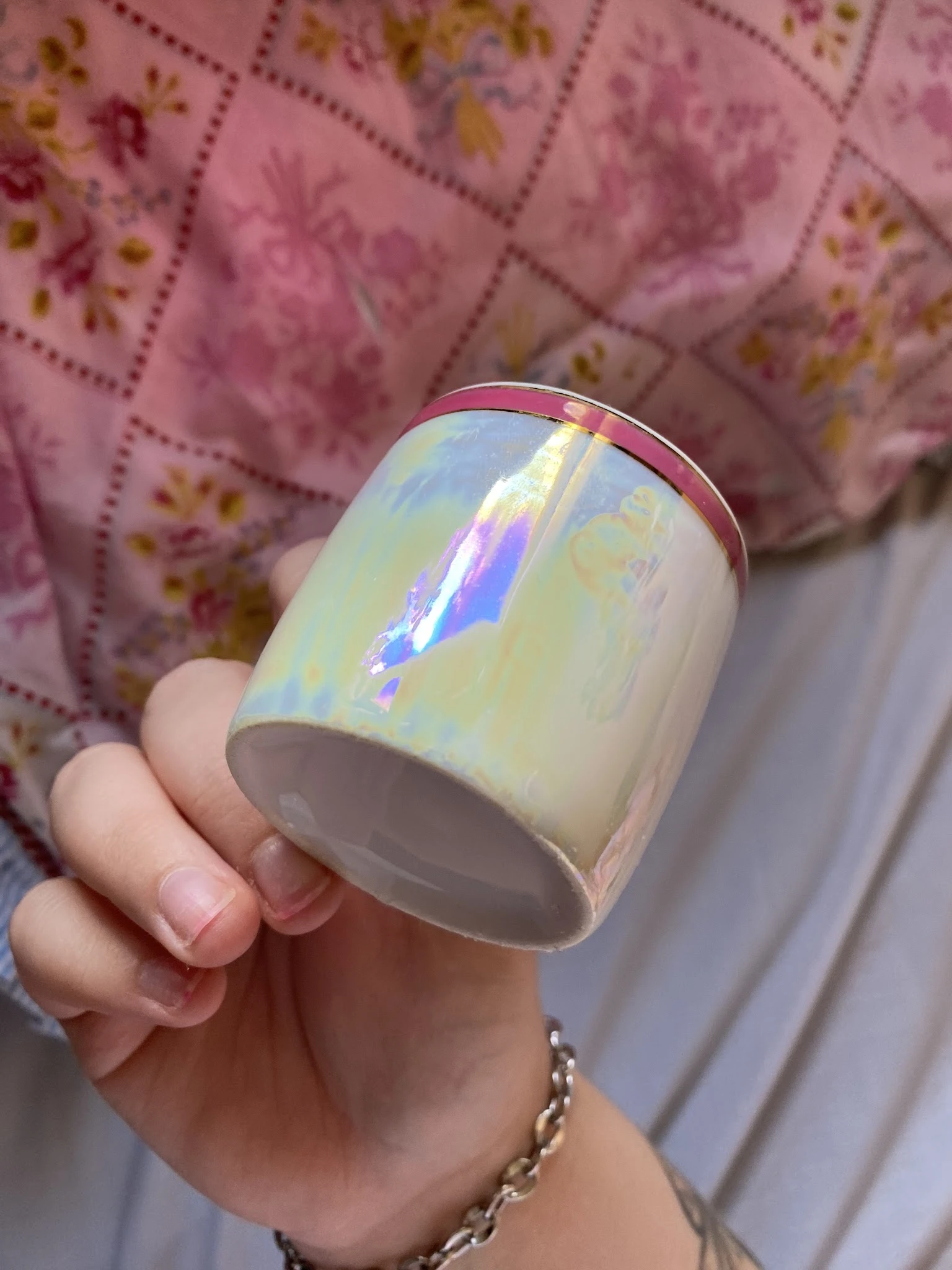 Close-up van een witte keramische mok met iriserende glazuur in een hand