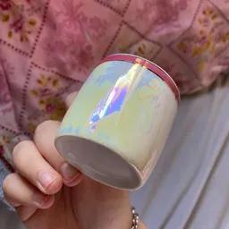 Close-up van een witte keramische mok met iriserende glazuur in een hand
