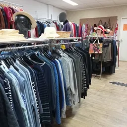 Rekken met tweedehands kleding in verschillende kleuren en maten in de winkel