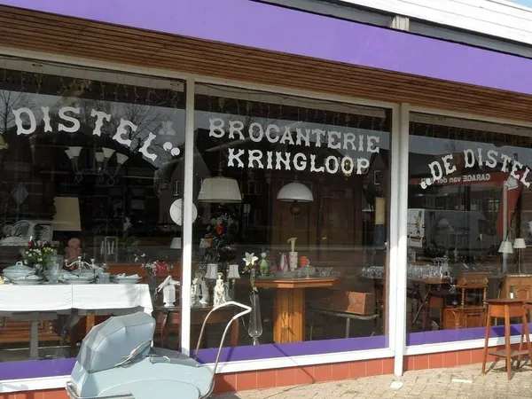 Winkelfront met paarse bovenkant en witte pui, met zichtbare winkelnaam en etalage vol decoratieve items