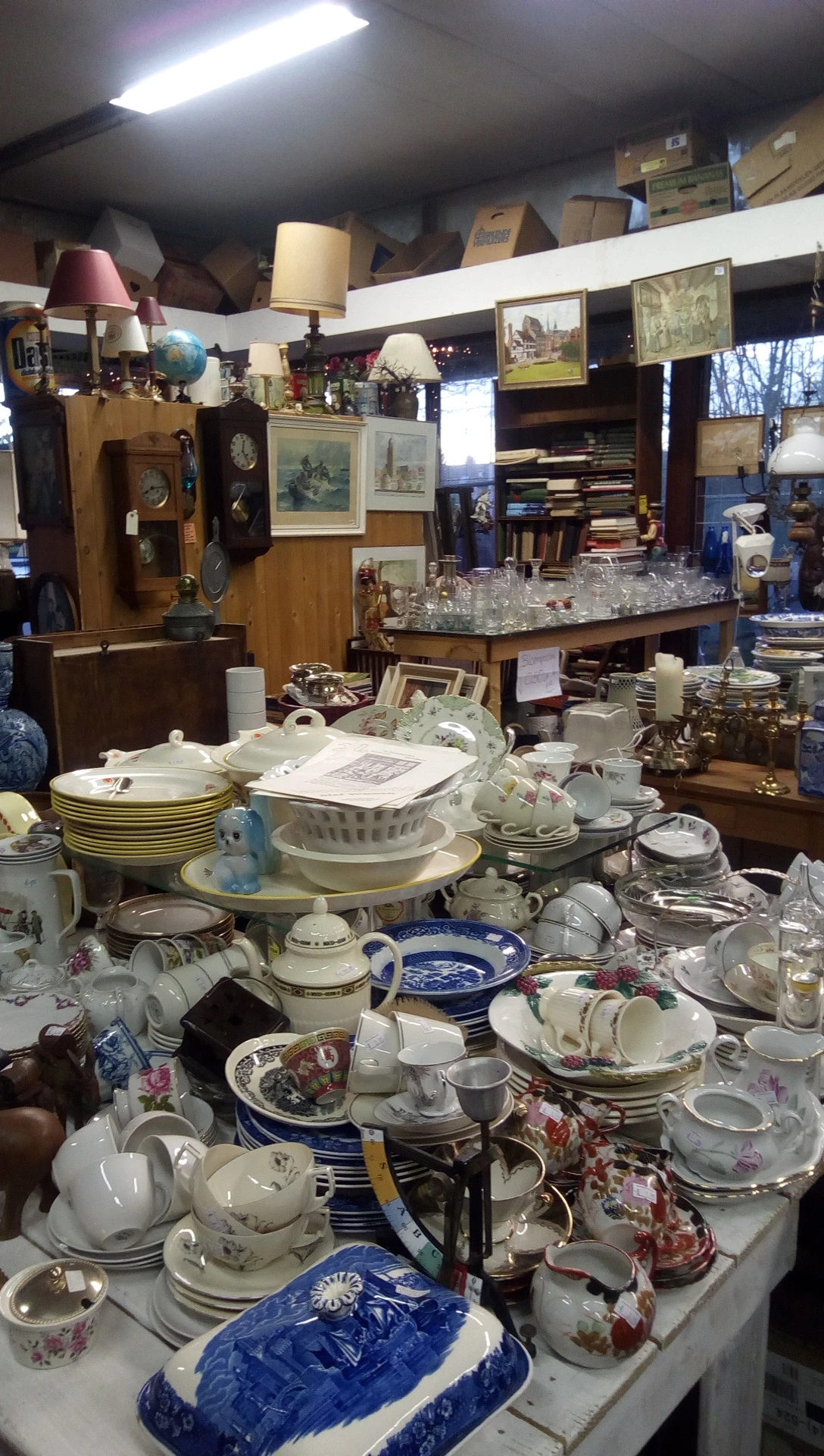 Uitgestalde servies, borden, kopjes en glazen in een kringloopwinkel