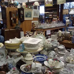 Uitgestalde servies, borden, kopjes en glazen in een kringloopwinkel