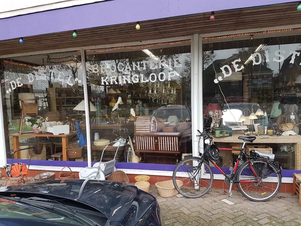 Winkelgevel met vitrines vol meubels, servies en decoratie, fiets vooraan, paarse luifel