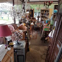 Binnenaanzicht van kringloopwinkel met meubels, lampen, servies en diverse spullen uitgestald