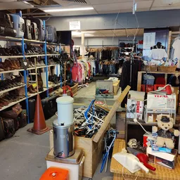 Winkelvloer met stellingen vol schoenen, kleding aan rekken, dozen en huishoudelijke artikelen