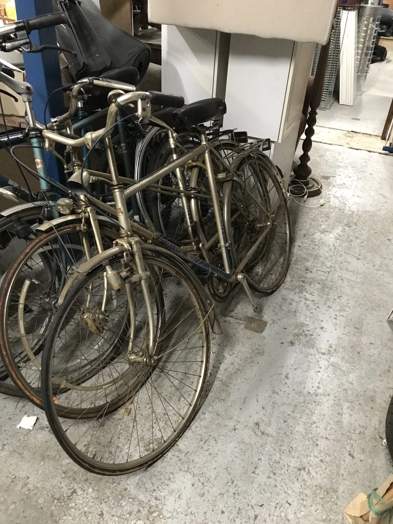 Tweedehands fietsen tegen elkaar aan in een opslagruimte op betonnen vloer
