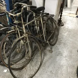 Tweedehands fietsen tegen elkaar aan in een opslagruimte op betonnen vloer