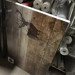 Donkere winkelvloer met houten planken en schaduw van een persoon, diverse items langs de rand zichtbaar