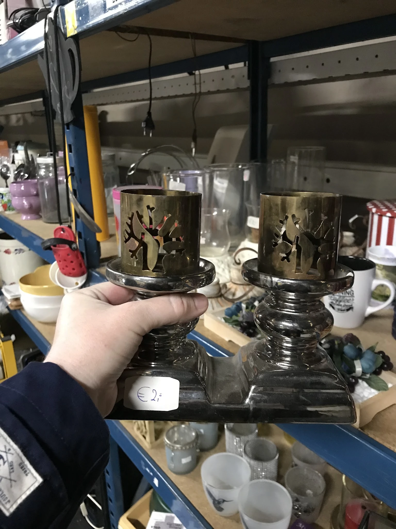 Twee zware zwarte kandelaars met gouden decoratief motief, vastgehouden in hand