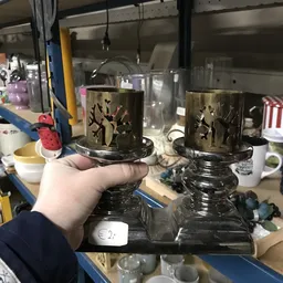 Twee zware zwarte kandelaars met gouden decoratief motief, vastgehouden in hand