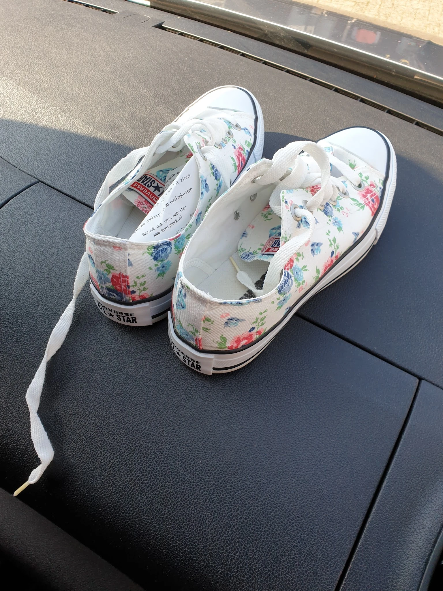 Witte sneakers met bloemenprint en witte veters op grijze ondergrond