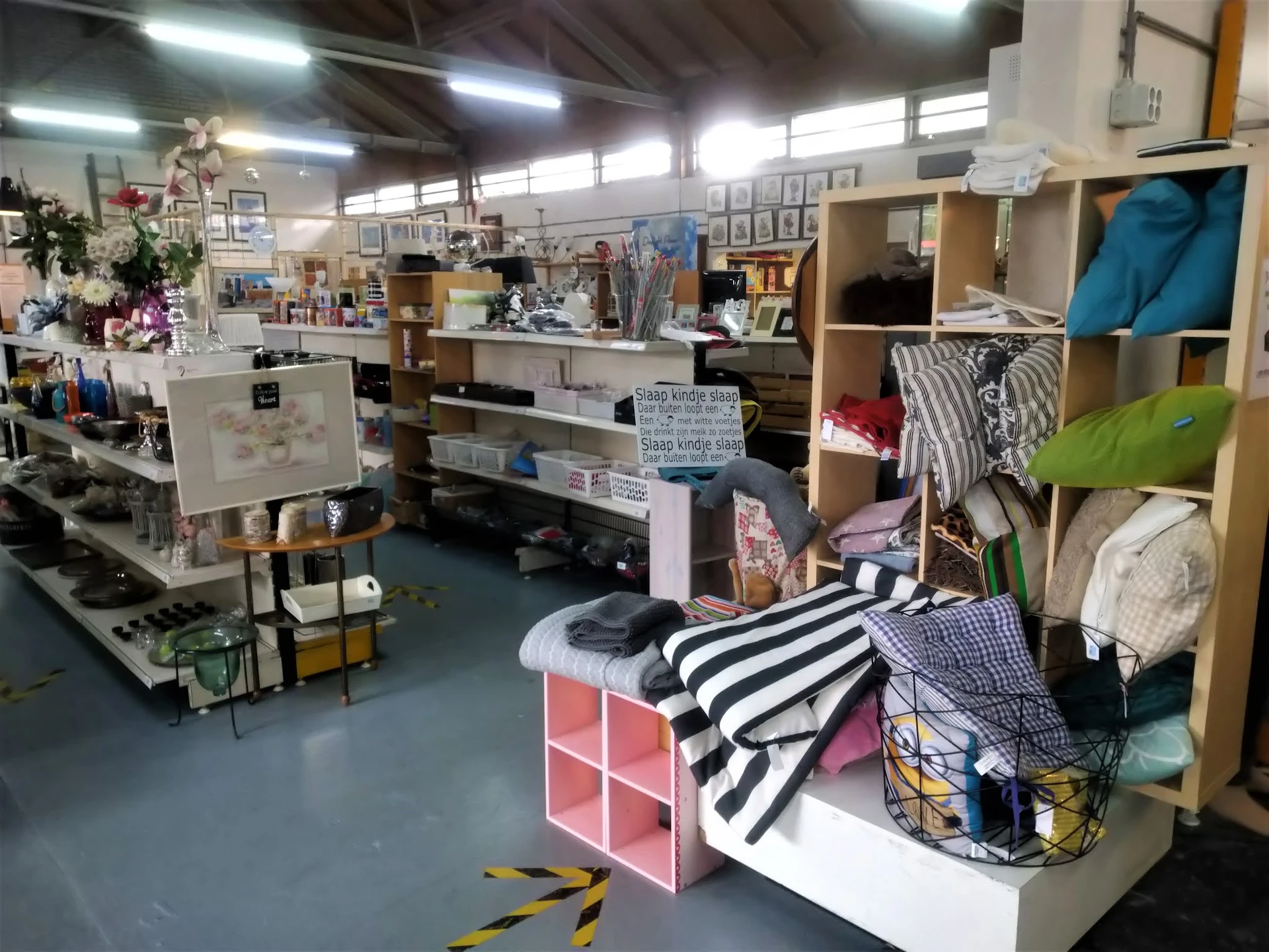 Overzicht van kringloopwinkel met stellingen vol kleding, huishoudartikelen en inrichtingsspullen