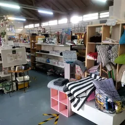 Overzicht van kringloopwinkel met stellingen vol kleding, huishoudartikelen en inrichtingsspullen