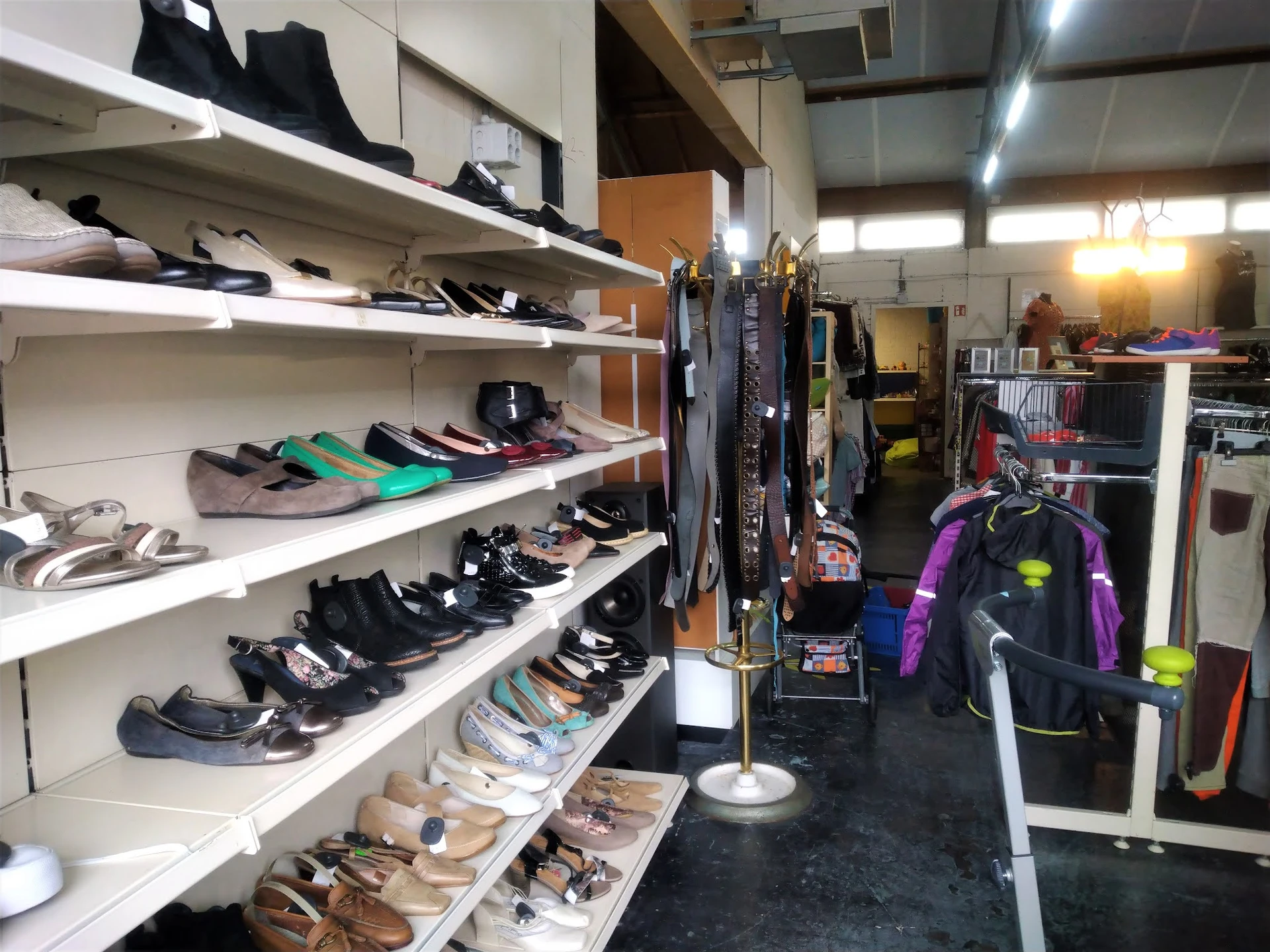Witte stellingen met uitgestalde tweedehands schoenen en sportartikelen in de winkel