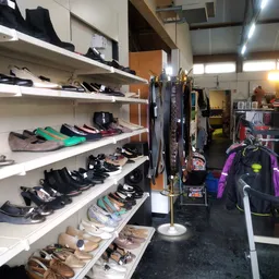 Witte stellingen met uitgestalde tweedehands schoenen en sportartikelen in de winkel
