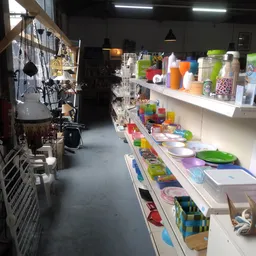 Winkelvloer van kringloopwinkel met stellingen vol huishoudelijke artikelen, keukengerei en decoratieve items in verschillend