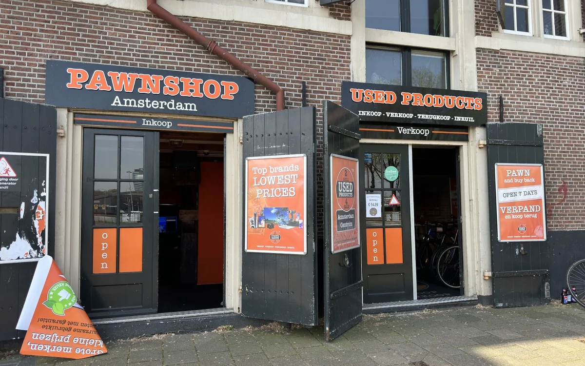 Gevel van twee panden met pawnshop en gebruikt goederen winkels, zwart met oranje accenten