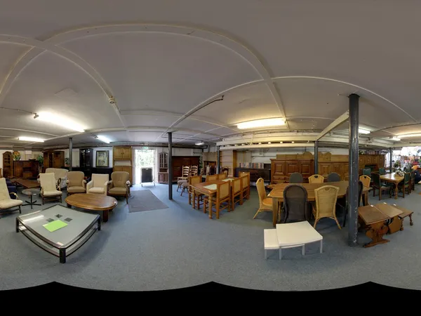 Ruim winkelbinnenland met meubels, houten stoelen en zittingsgelegenheden uitgestald onder ronde plafondconstructie
