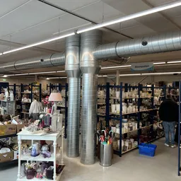Winkelvloer met stellingen vol spullen, vitrinekastjes en displaytafels in een kringloopwinkel