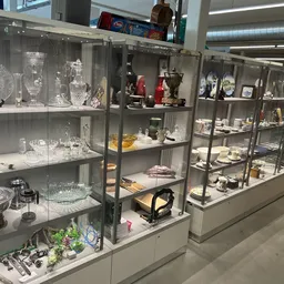 Glazen vitrinekasten met verzameling van serviesgoed, glaswerk, beeldjes en decoratieve objecten