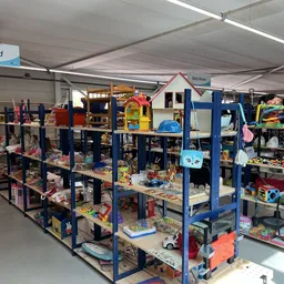 Magazijnruimte met blauwe stellingen vol speelgoed, kinderartikel en diverse tweedehands goederen