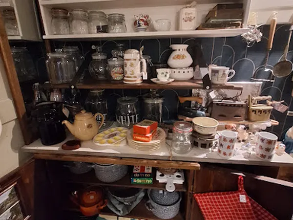 Planken met huishoudelijke items: kopjes, potten, kannen, glazen en ander keukengerei