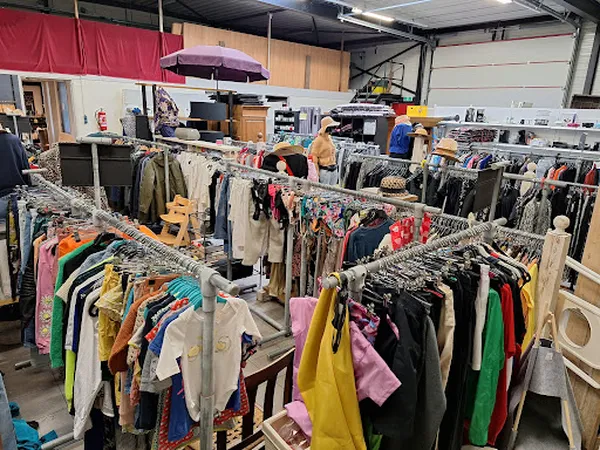Rekken met tweedehands kleding in verschillende kleuren en stijlen in een kringloopwinkel