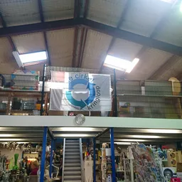 Overzicht van de winkelvloer met stellingen, rekken met kleding en spullen, trappartij naar bovenverdeping
