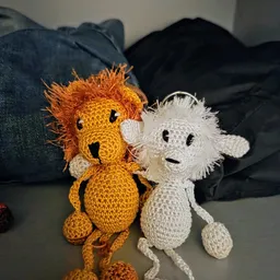 Twee gehaakt knuffelbeesten: een oranje leeuw en een witte beer naast elkaar