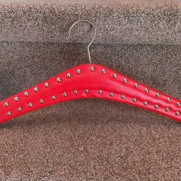 Rode kledinghanger met zilveren studs op bruine achtergrond