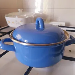 Blauwe emaille pan met deksel en gouden rand op gasfornuis