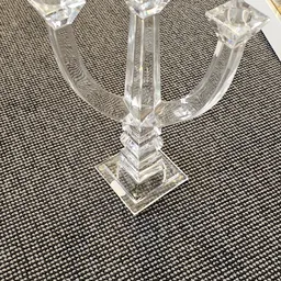 Close-up van de voet en onderste deel van een glazen kandelaar met vierkante basis