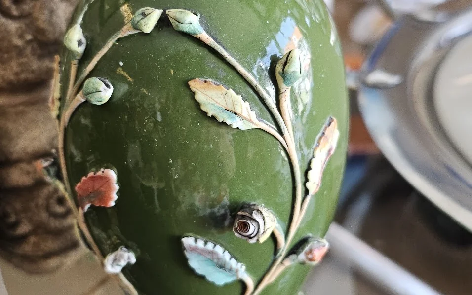 Groene decoratieve vaas met bloemen- en bladmotieven in reliëf, close-up detail