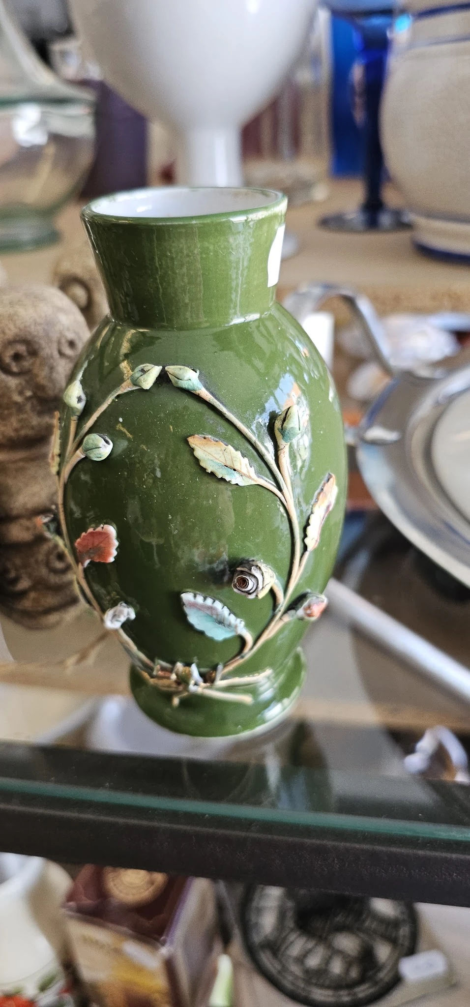 Groene decoratieve vaas met bloemen- en bladmotieven in reliëf, close-up detail