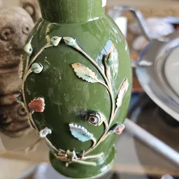 Groene decoratieve vaas met bloemen- en bladmotieven in reliëf, close-up detail