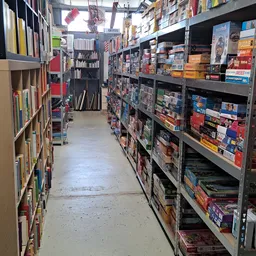Gang tussen rekken met tweedehands boeken, dvd's en spellen in de kringloopwinkel