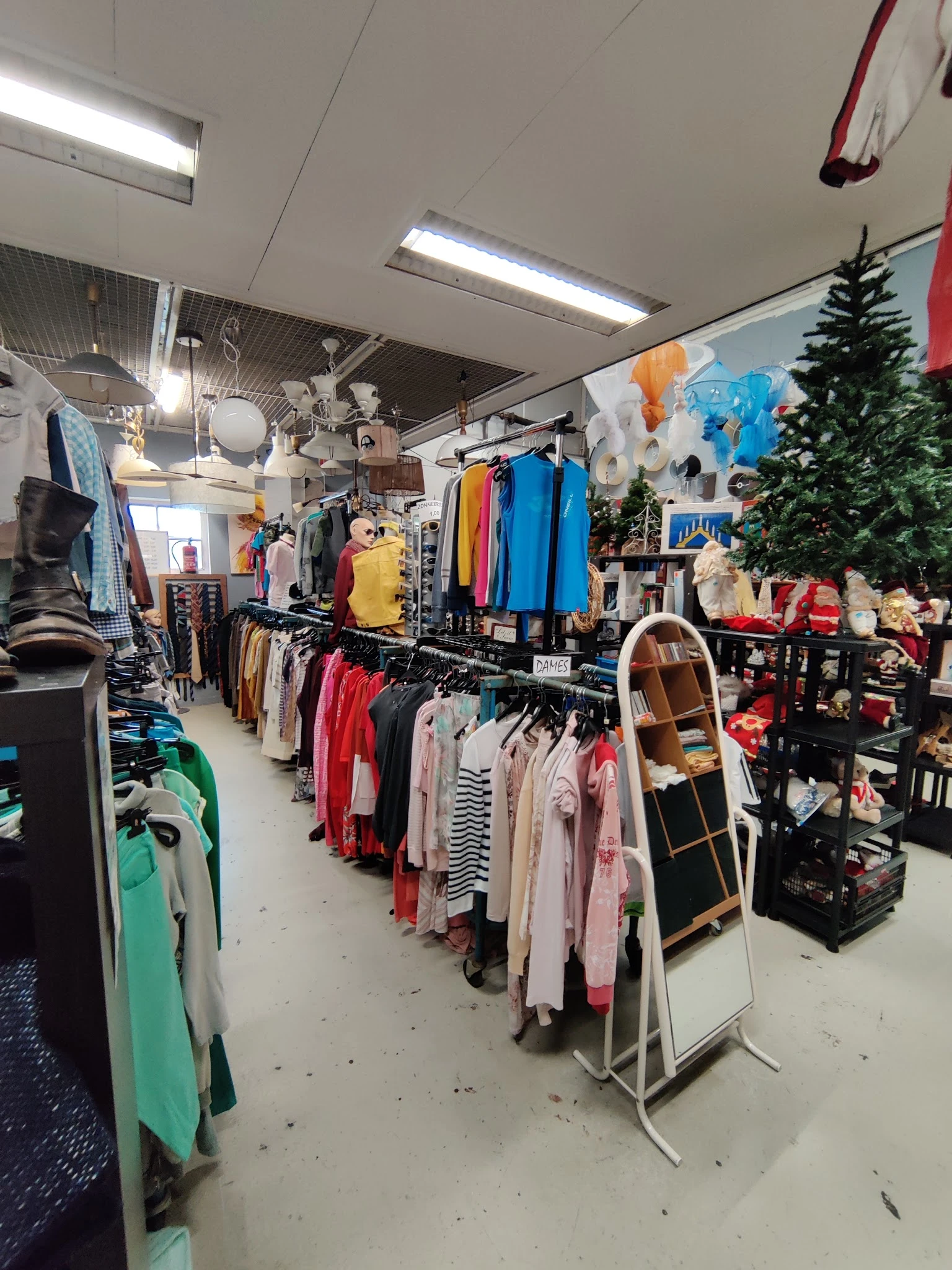 Winkelvloer met kledingrekken, mannequins en kerstvering in een kringloopwinkel