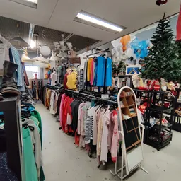 Winkelvloer met kledingrekken, mannequins en kerstvering in een kringloopwinkel